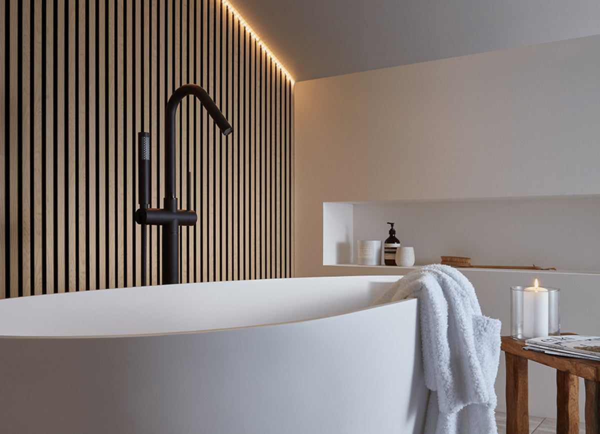 SlatWall Waterproof on wall behind white bath with black tap. Strip lighting to highlight the wood effect texture.