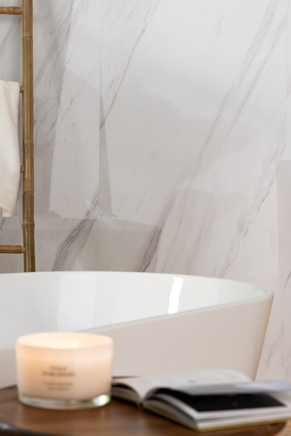 Elemence Shower Panels Calacatta White close up of grey marbling. Corner of bath with candle and book