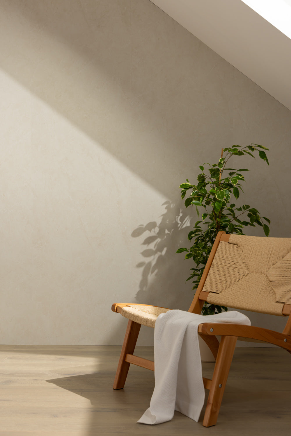 Elemence Shower Panels Chalk Beige on wall with shadow. Wooden chair in front and plant.