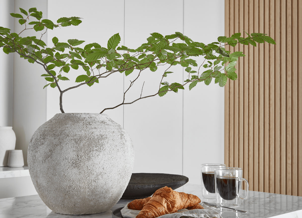 Large rounded stone vase on top of kitchen island with marble top.