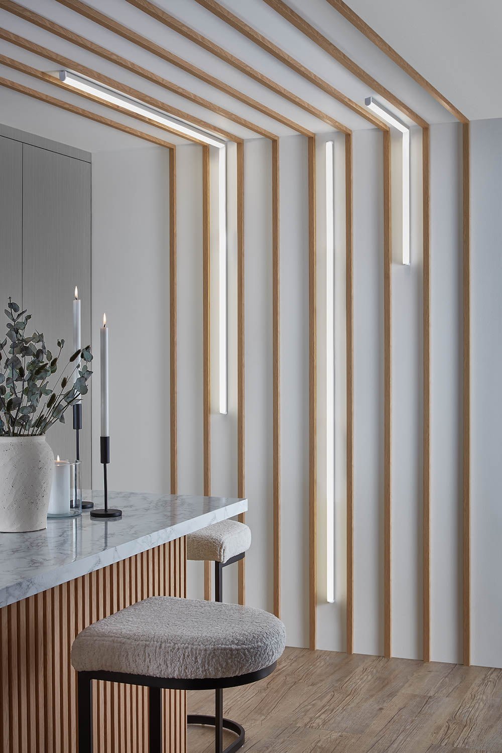 Waterproof individual slats spaced out on a kitchen wall with strip lighting between.