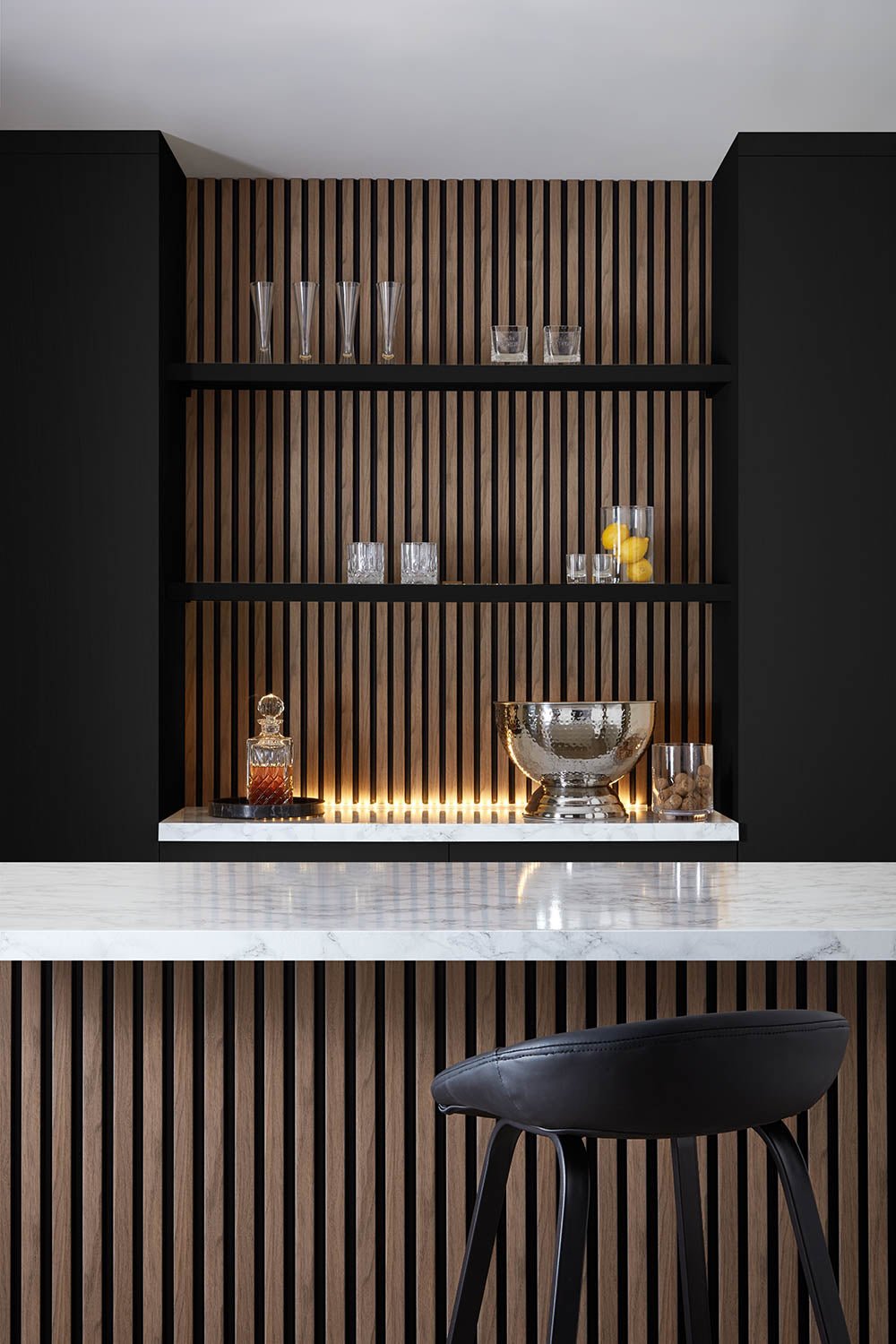 SlatWall Waterproof walnut and black panels used in home bar area. Black walls with panelling and shelves in the centre